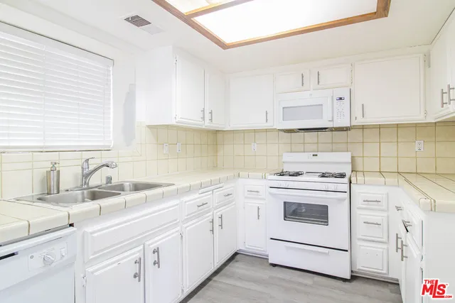 a kitchen with white cabinets sink and white appliances