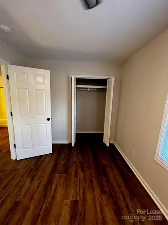 a view of an empty room with wooden floor and closet