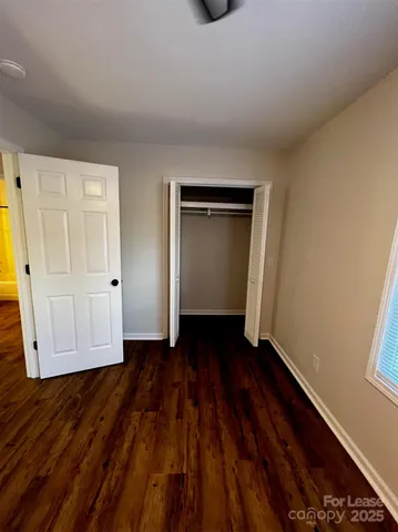 a view of an empty room with wooden floor and closet