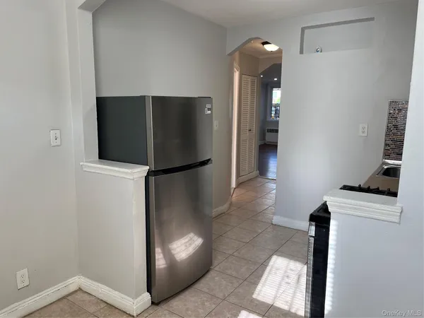 a view of a refrigerator in kitchen and an empty room