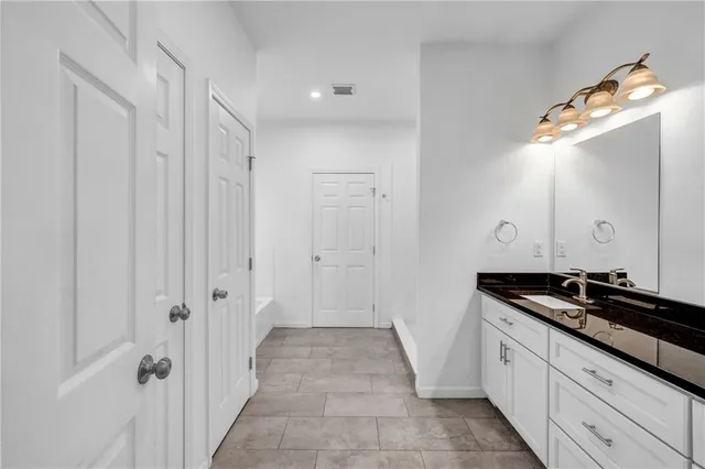 a spacious bathroom with a granite countertop sink and a mirror