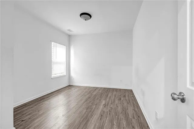 an empty room with a window and wooden floor