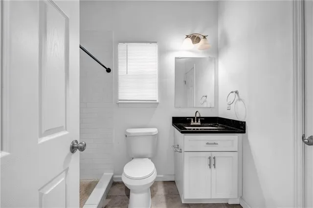 a bathroom with a granite countertop sink toilet and mirror