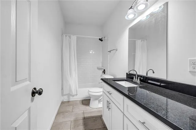 a bathroom with a granite countertop sink a toilet a mirror and shower
