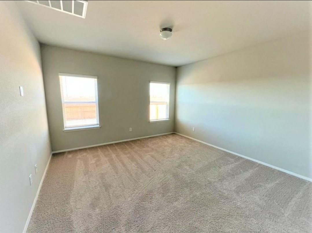 2771 Winding Creek Road Kyle, TX 78640 - Photo 9 of 24 A spacious room offers comfortable carpet flooring and natural illumination through multiple windows.
