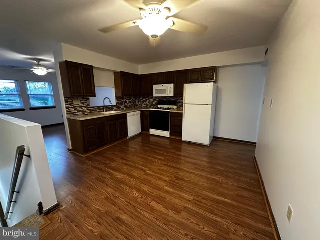 a kitchen with stainless steel appliances granite countertop a stove top oven a sink dishwasher and a refrigerator with wooden floor