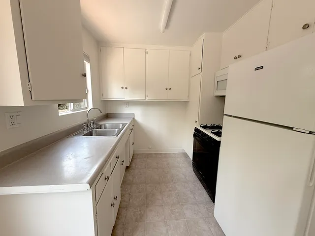 a kitchen with granite countertop a sink a stove and refrigerator