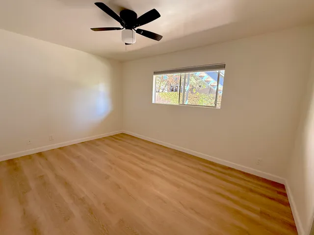 an empty room with a window and a ceiling fan