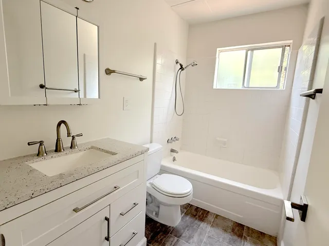 a bathroom with a granite countertop toilet a sink and a bathtub