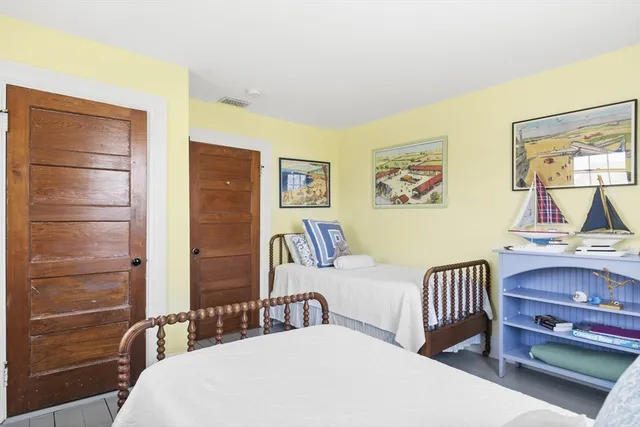 a bedroom with a bed and a table with potted plant on the dresser