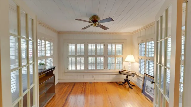 a view of a livingroom with a fireplace a ceiling fan and windows