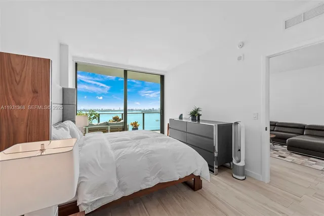 a bedroom with a bed a large window and wooden floor