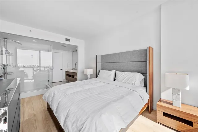 a large bed in a white room with a mirror