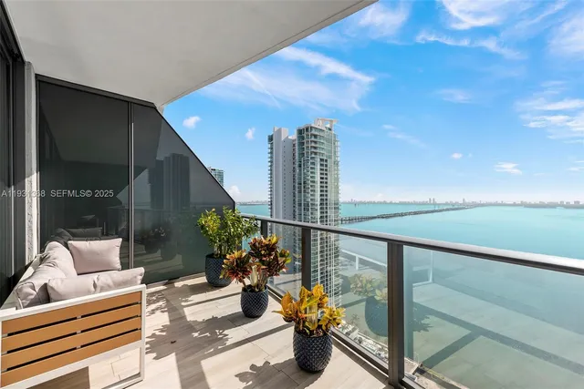a balcony with couple of chairs and potted plants