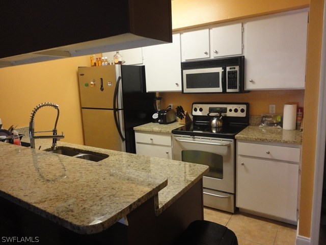 5307 Summerlin Road, Unit 710 Fort Myers, FL 33919 - Photo 2 of 19 a kitchen with granite countertop a sink a stove and a microwave with wooden floor
