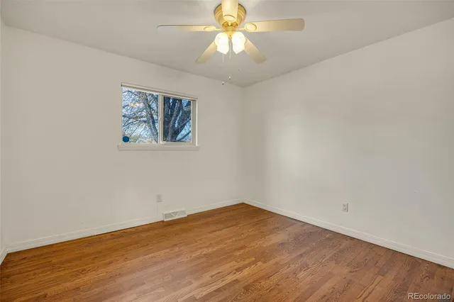 an empty room with a window and a chandelier fan
