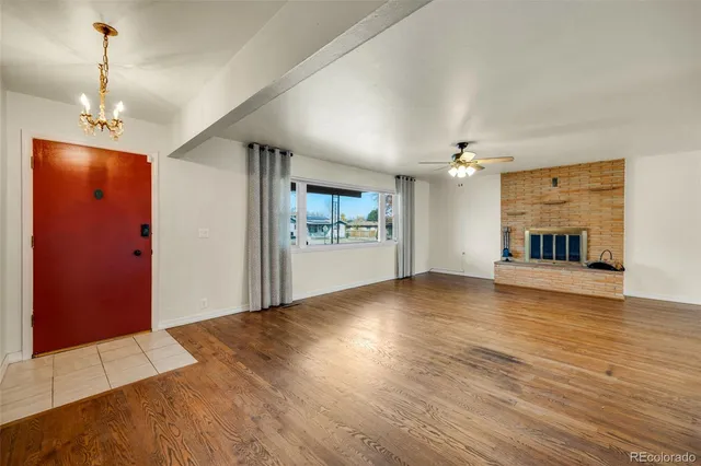 an empty room with wooden floor fireplace and windows