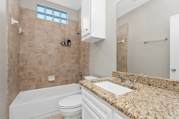 a bathroom with a granite countertop sink a toilet and shower