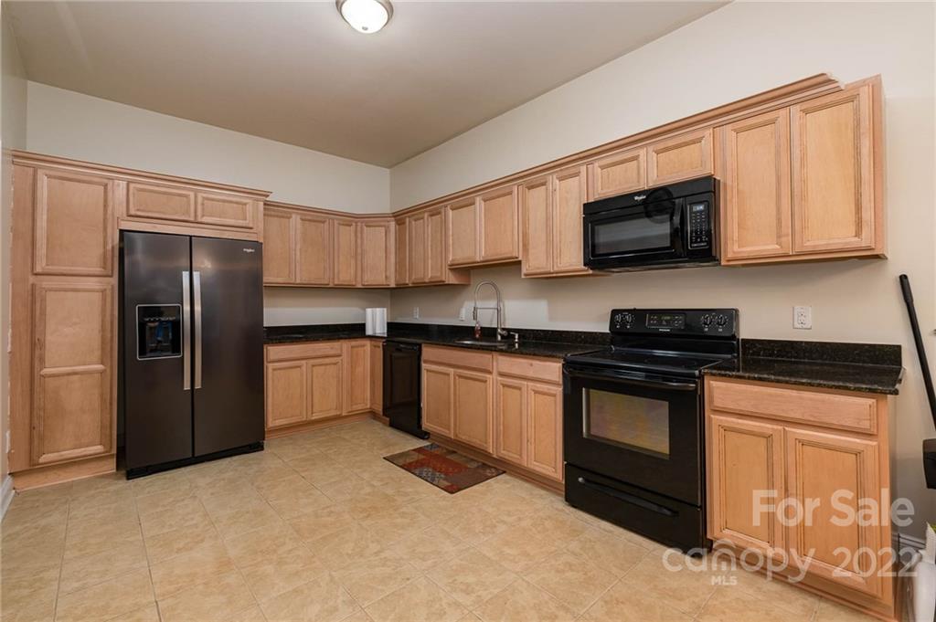 5712 Davis Road Waxhaw, NC 28173 - Photo 32 of 43 a kitchen with granite countertop a refrigerator and a stove top oven