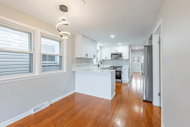 a kitchen with stainless steel appliances granite countertop a refrigerator a sink a stove and oven with wooden floor