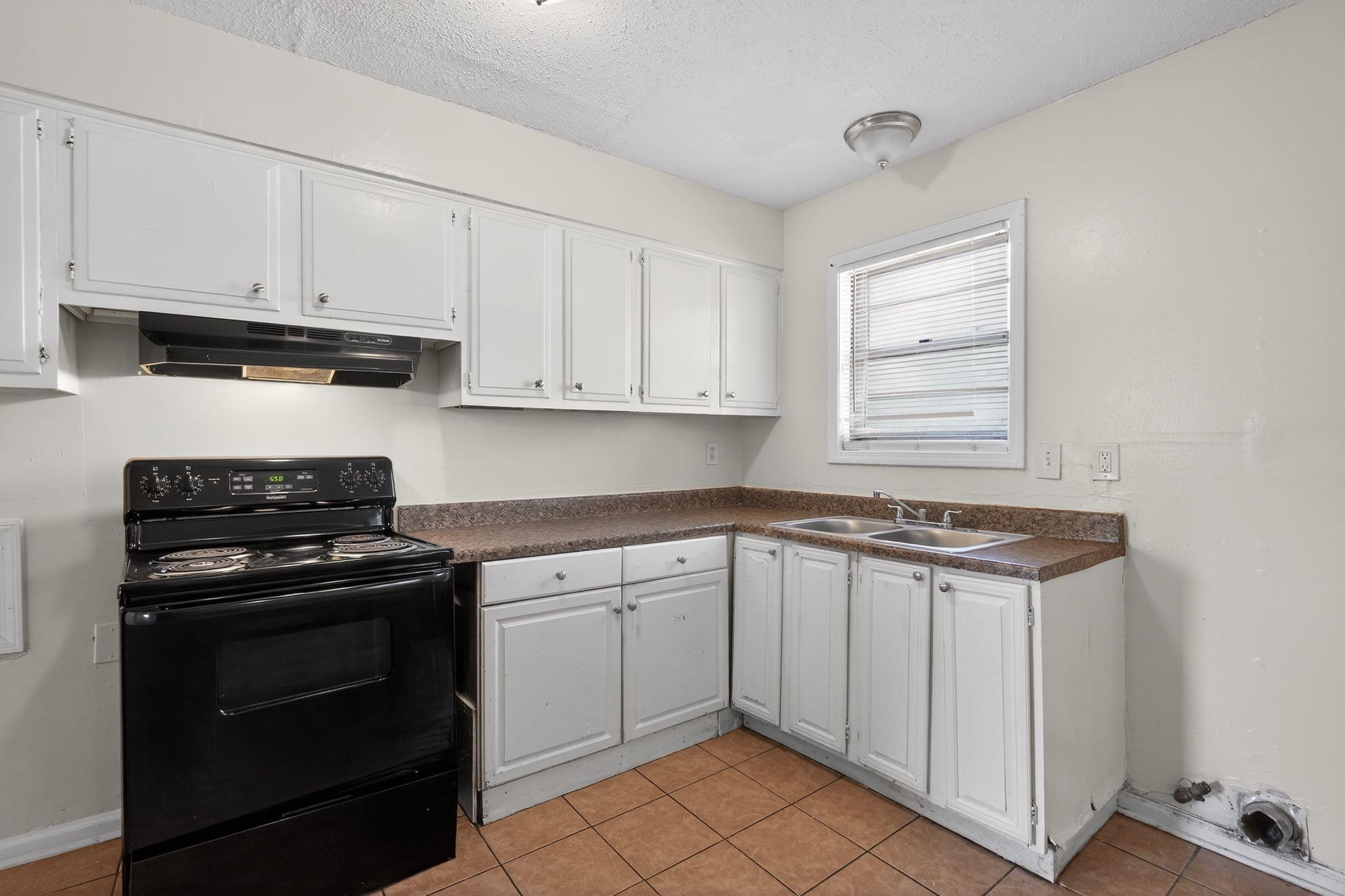 3637 Neely Road Memphis, TN 38109 - Photo 10 of 30 Kitchen featuring electric range, white cabinets, dark countertops, light tile patterned flooring, and a textured ceiling