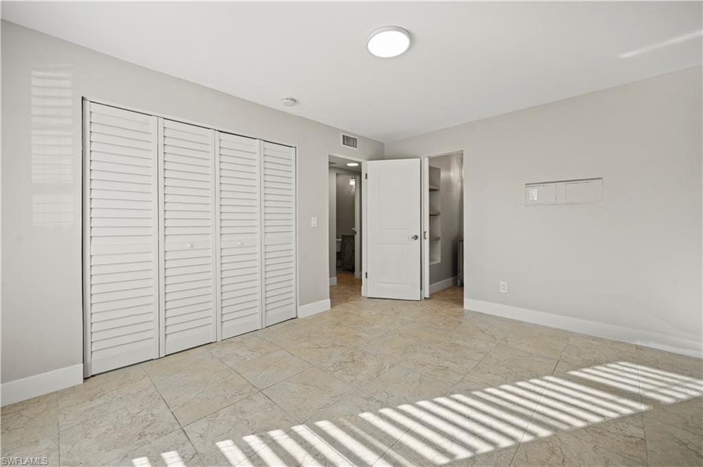 3 Kings Road, Unit A7 Naples, FL 34112 - Photo 11 of 20 Unfurnished bedroom featuring a closet and ensuite bath
