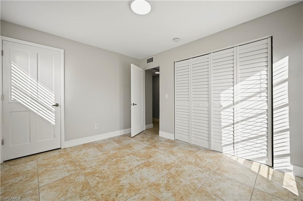 3 Kings Road, Unit A7 Naples, FL 34112 - Photo 14 of 20 Unfurnished bedroom with a closet and light tile patterned floors