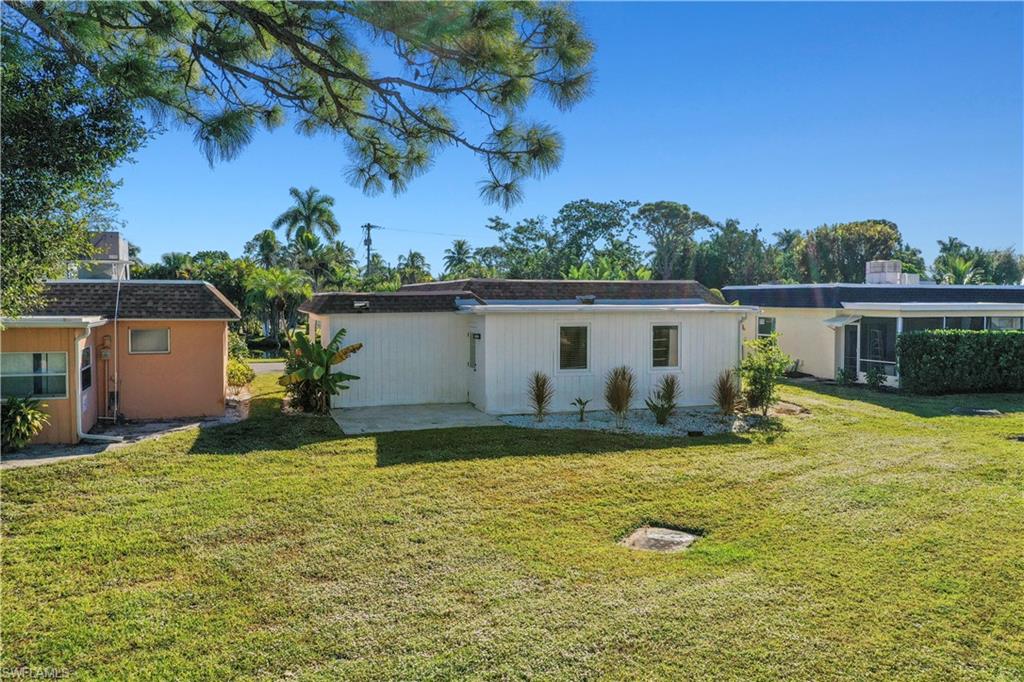 3 Kings Road, Unit A7 Naples, FL 34112 - Photo 18 of 20 Rear view of property featuring a lawn