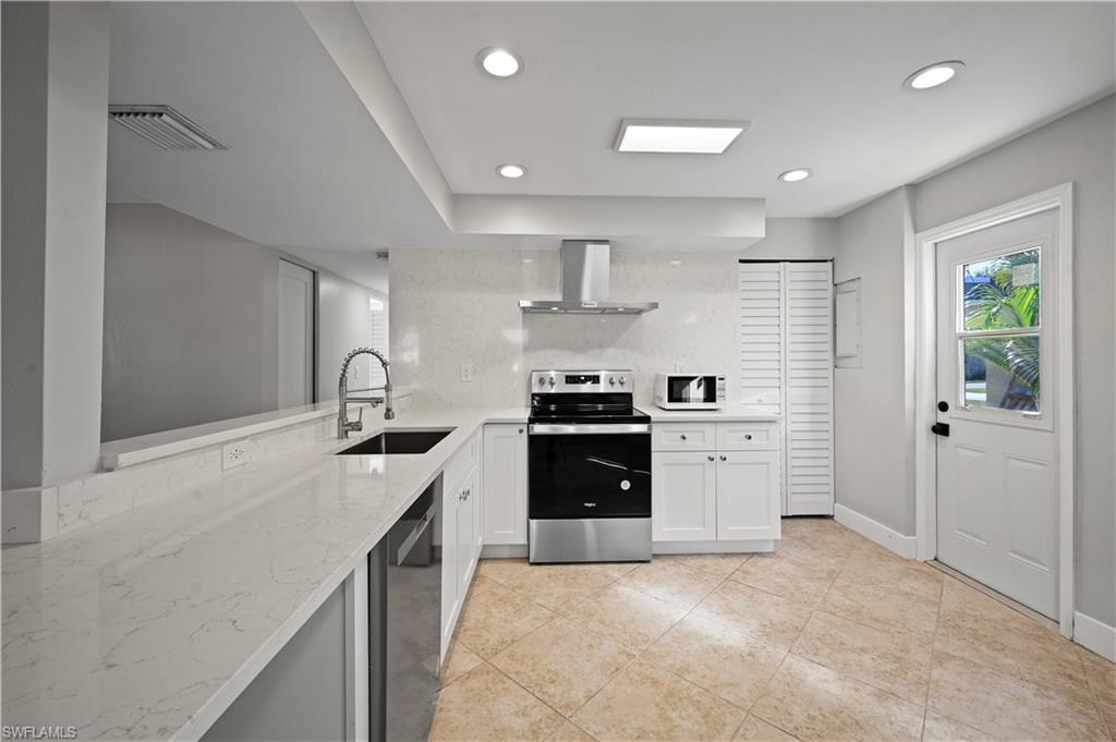 3 Kings Road, Unit A7 Naples, FL 34112 - Photo 6 of 20 Kitchen featuring stainless steel appliances, light stone counters, exhaust hood, recessed lighting, and backsplash