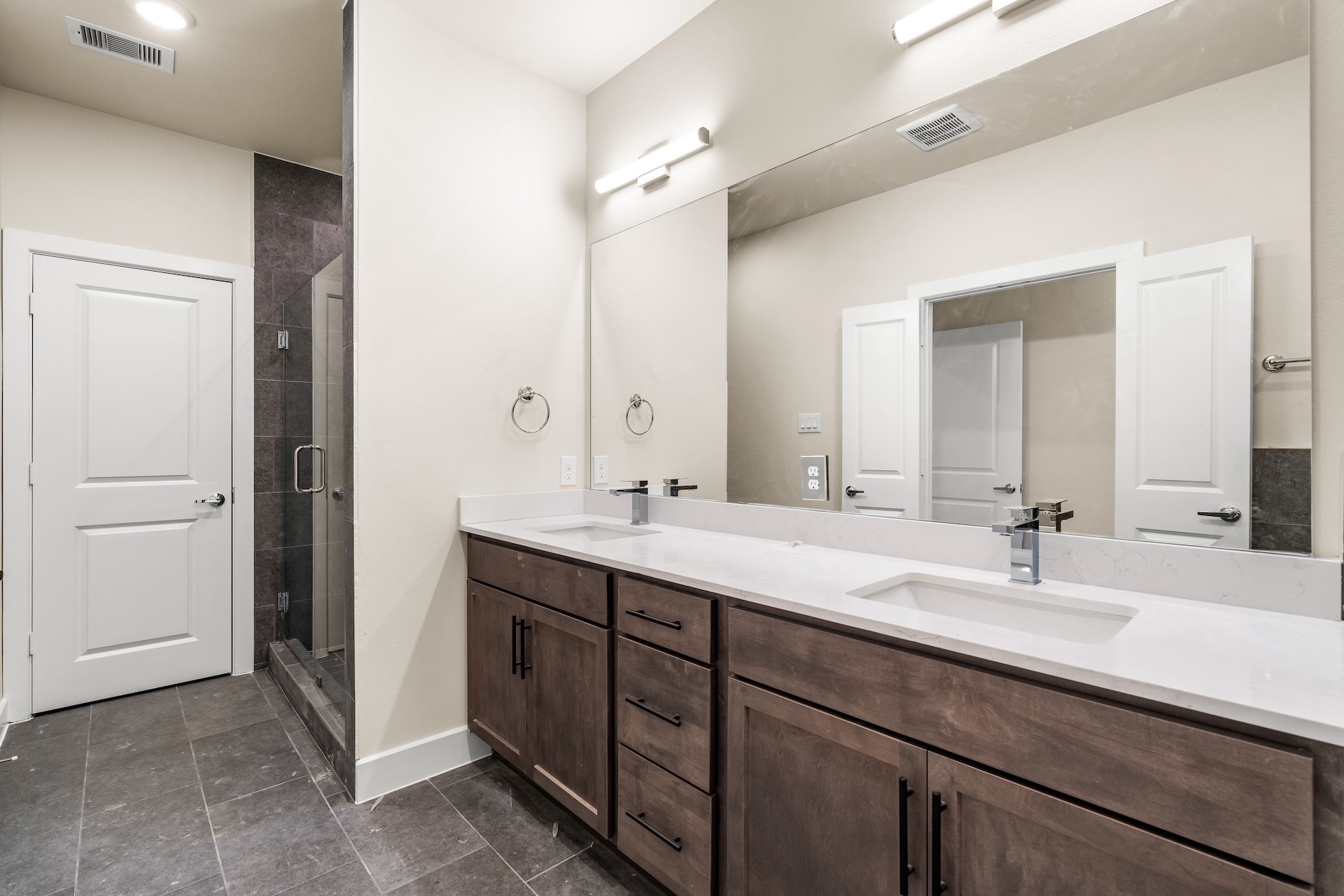 6521 Rena Street Houston, TX 77092 - Photo 17 of 24 Expansive primary bathroom vanity — extended quartz countertop with dual undermount sinks, stained wood shaker cabinetry, dark floor tile, and linear LED vanity bar lighting.