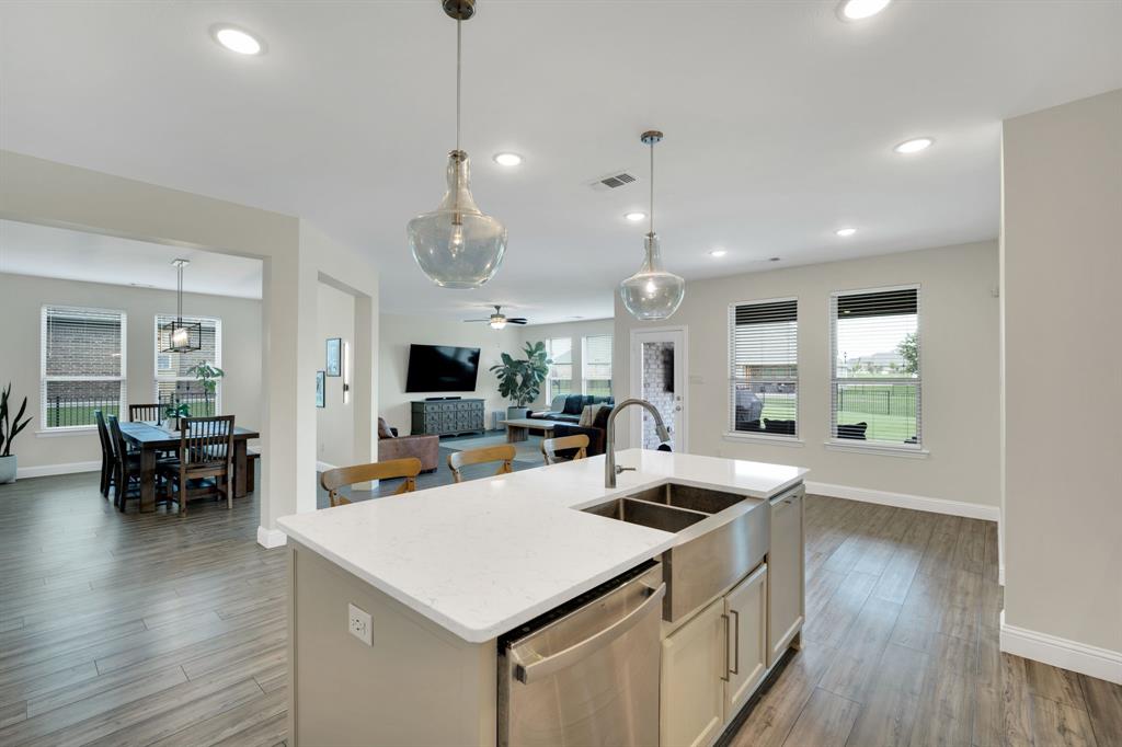 1601 Bear Path Way Gunter, TX 75058 - Photo 4 of 40 a kitchen with a counter top space a sink dishwasher a dining table and chairs with wooden floor