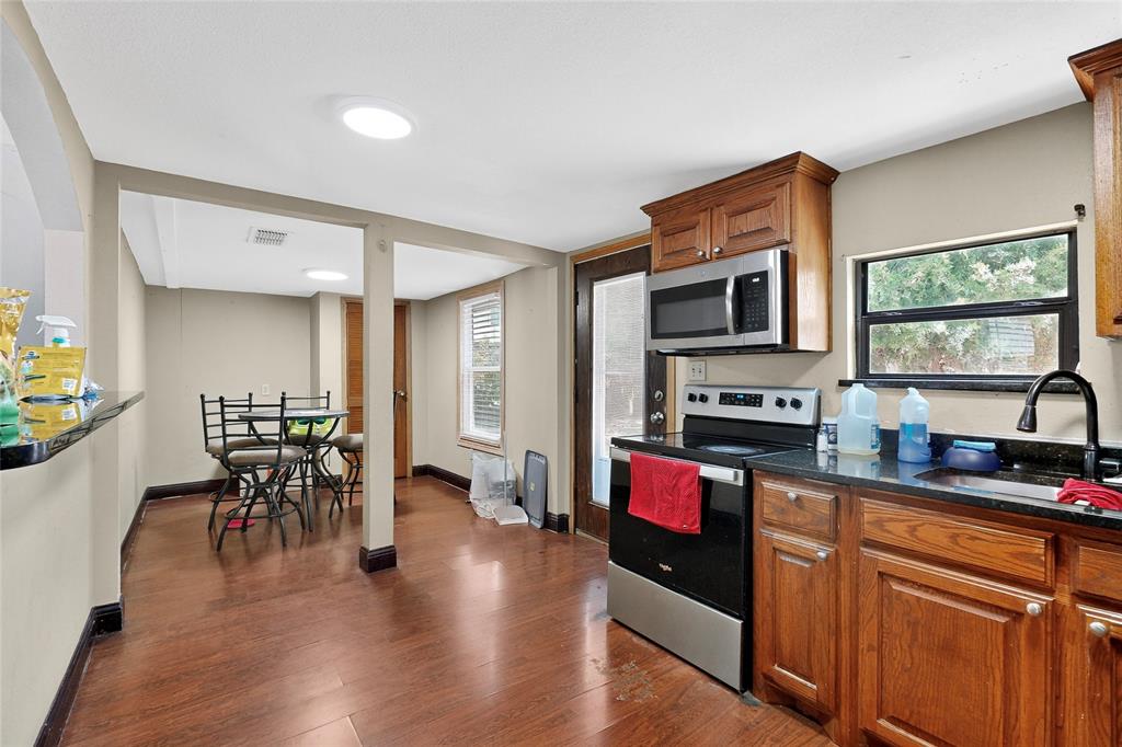 940 Rowlett Road Rowlett, TX 75088 - Photo 22 of 37 a kitchen with stainless steel appliances granite countertop a stove top oven a sink dishwasher a dining table and chairs with wooden floor