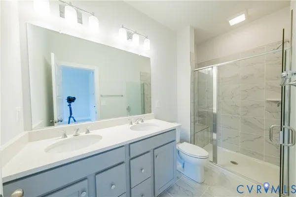 a bathroom with a shower sink vanity mirror and toilet