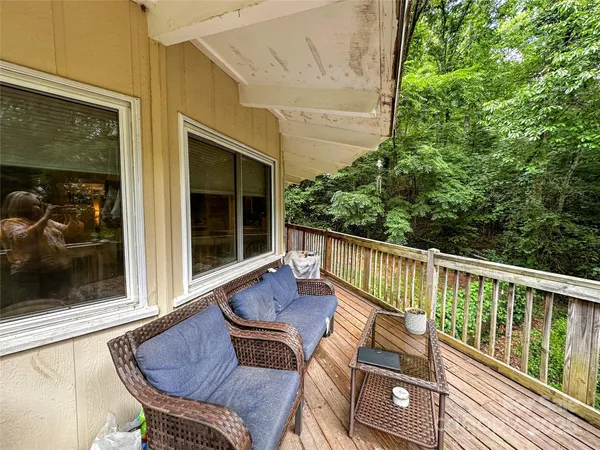 a view of deck with furniture and trees in the background