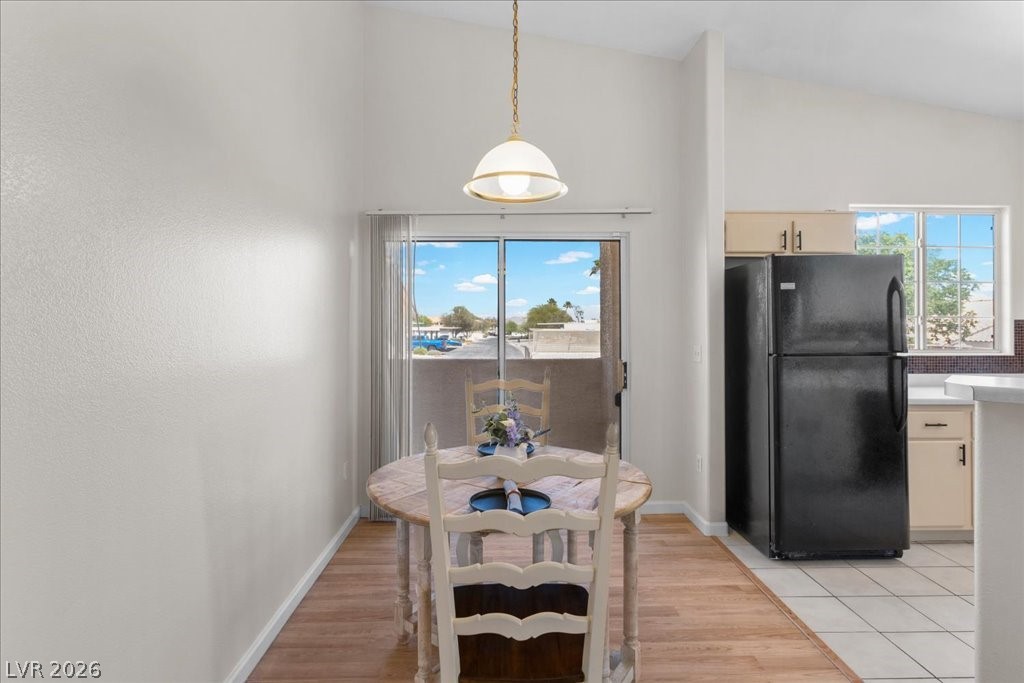 1881 West Alexander Road, Unit 1037 North Las Vegas, NV 89032 - Photo 12 of 31 A well-lit dining area featuring a vaulted ceiling and a sliding glass door leading to a balcony.