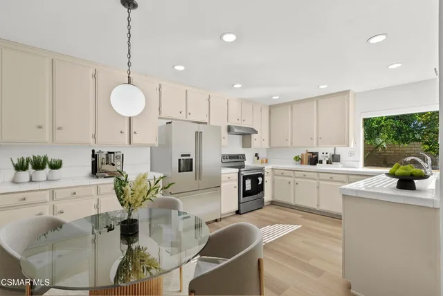 a kitchen with stainless steel appliances kitchen island granite countertop a refrigerator a stove a sink dishwasher and white cabinets with wooden floor