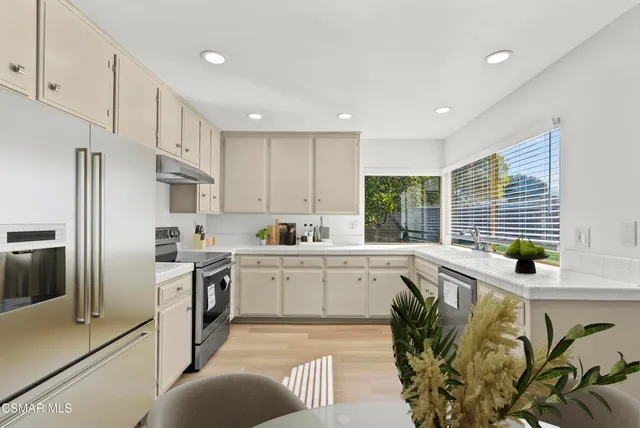 a kitchen with stainless steel appliances granite countertop a sink a stove a refrigerator and cabinets