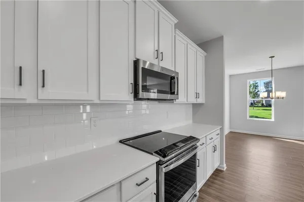 a kitchen with stainless steel appliances white cabinets and a stove top oven
