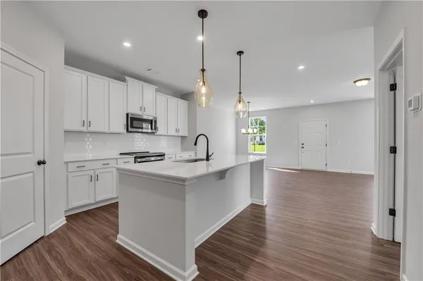 a large kitchen with stainless steel appliances sink a microwave and wooden floor
