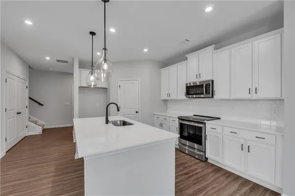 a kitchen with stainless steel appliances granite countertop a sink a stove top oven a counter space and cabinets
