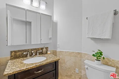 a bathroom with a granite countertop sink and a toilet