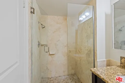 a bathroom with a granite countertop shower and a sink