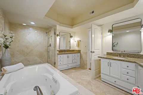 a bathroom with a granite countertop sink a large mirror and a bathtub