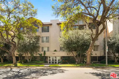 a view of a white house with a large tree and a yard