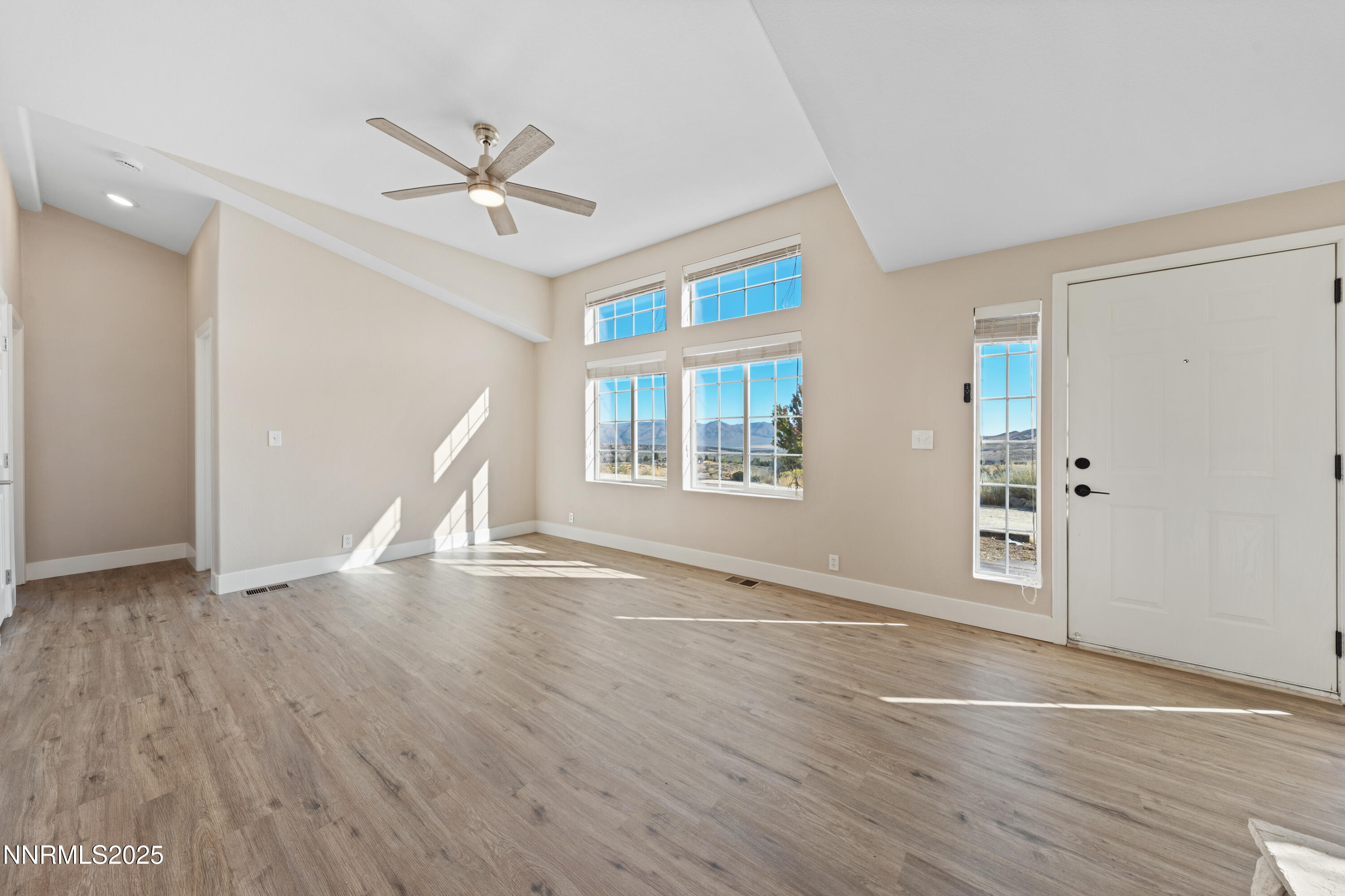 15190 North Red Rock Road Reno, NV 89508 - Photo 16 of 55 an empty room with wooden floor chandelier fan and windows