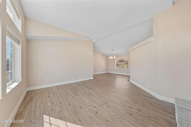 a view of an empty room with window and wooden floor