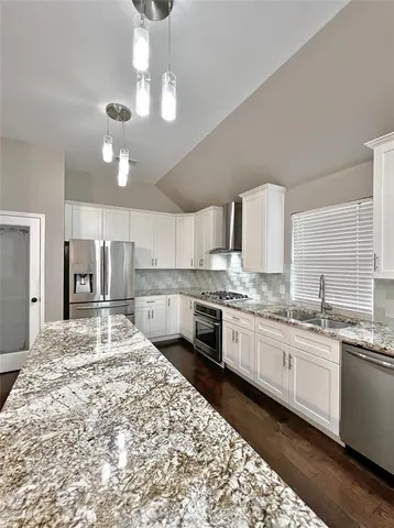 a large white kitchen with stainless steel appliances kitchen island granite countertop a large counter top and wooden floors