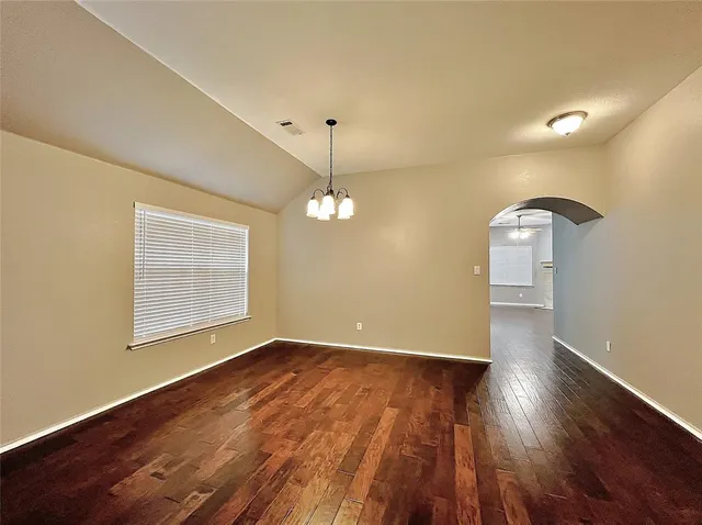 a view of an empty room with wooden floor and a fan