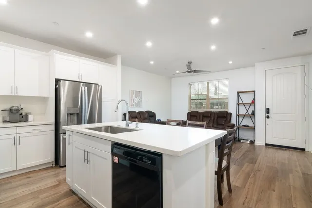 a kitchen with a sink a stove a refrigerator and white cabinets with wooden floor