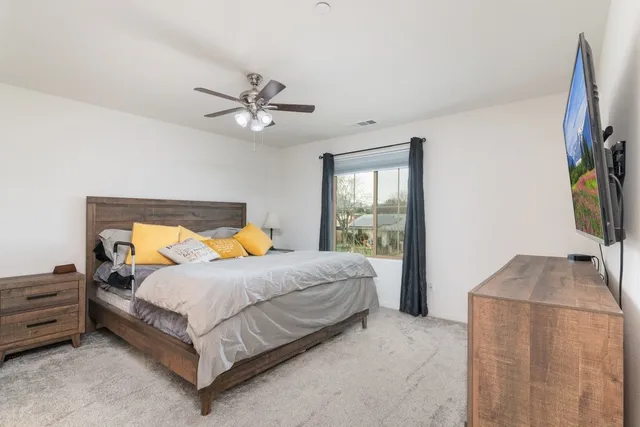 a bedroom with a bed and a flat tv screen on dresser